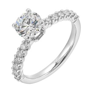 A dazzling round solitaire takes center stage, held by a sleek shank adorned with sparkling diamonds is a perfect choice for any occasion.