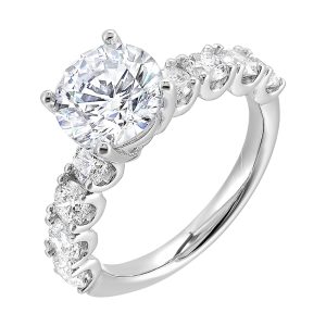 A solitaire engagement ring accommodates sparkling round diamonds of considerable size along the shank giving luxurous look.